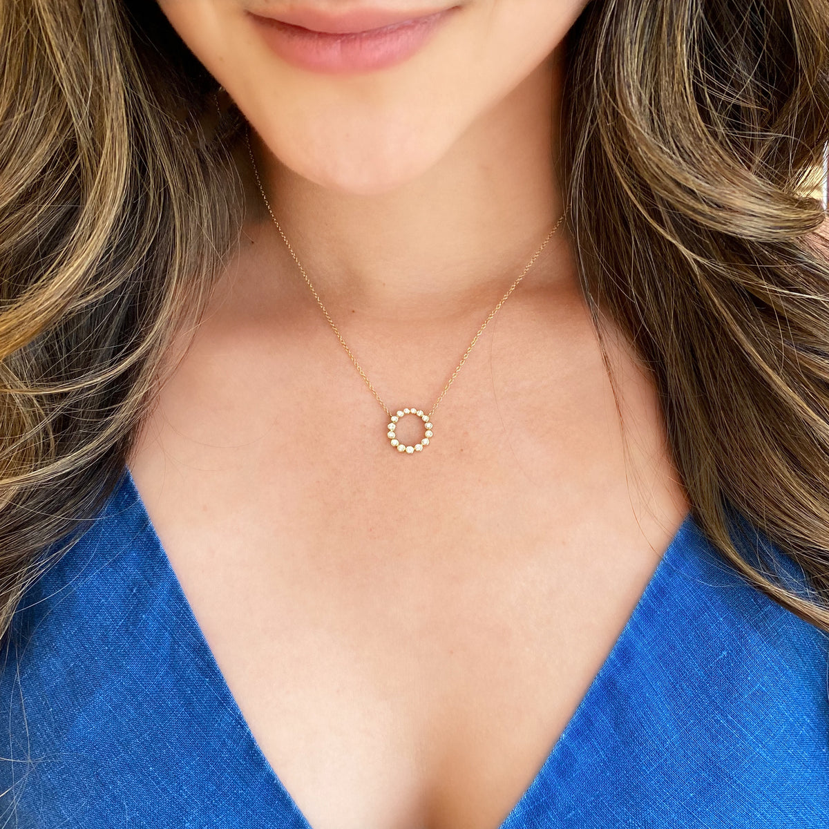 Female model wearing Bezel-Set Diamond Open Circle Pendant Necklace - 14K gold weighing 2.28 grams. - 15 Round Diamonds totaling 0.27 carats.