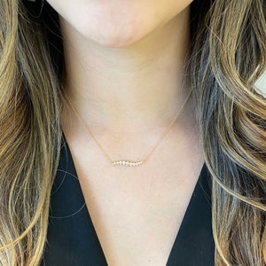 Female Model Wearing Diamond Wave Bar Necklace.  -14K gold weighing 1.83 grams  -11 round diamonds totaling 0.37 carats