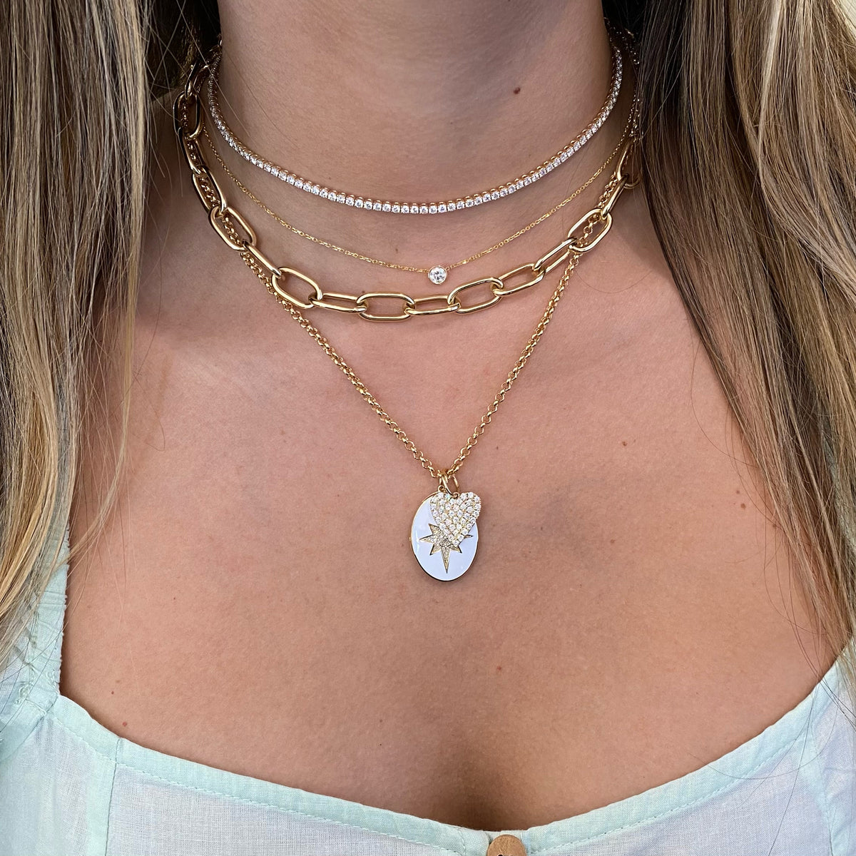 Female model wearing Diamond & Enamel Star Oval Locket Necklace - 14K yellow gold weighing 7.82 grams - 55 round diamonds totaling 0.14 carats