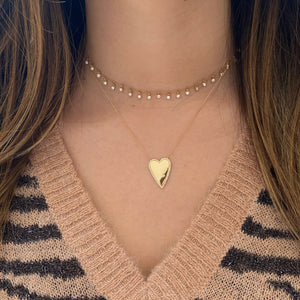 Female Model Wearing Diamond-Framed Elongated Heart Pendant  - 14K gold weighing 5.42 grams  - 58 round diamonds totaling 0.14 carats
