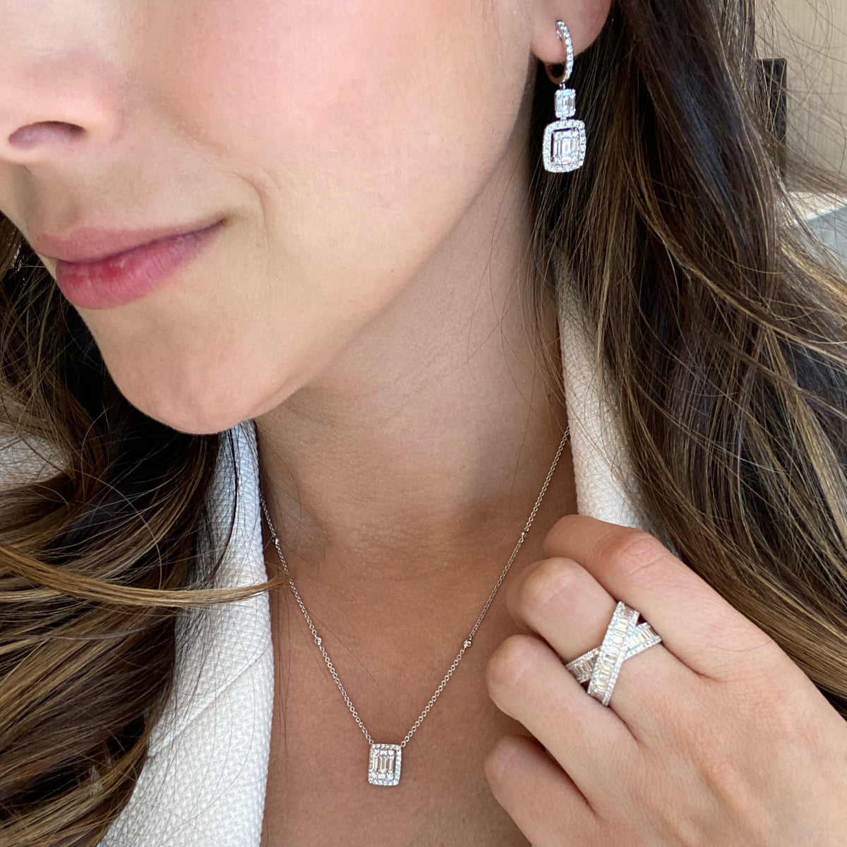 Female Model Wearing Emerald-Cut Diamond Illusion Dangle Earrings - 18K gold weighing 5.93 grams  - 20 slim baguettes weighing 1.03 carats  - 74 round diamonds weighing 0.93 carats