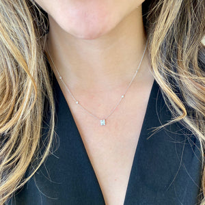 Female Model Wearing Diamond Rectangle Pendant with Bezel-Set Diamond Stations  - 14K gold weighing 2.02 grams  - 8 round diamonds totaling 0.14 carats  - 5 straight baguettes totaling 0.21 carats