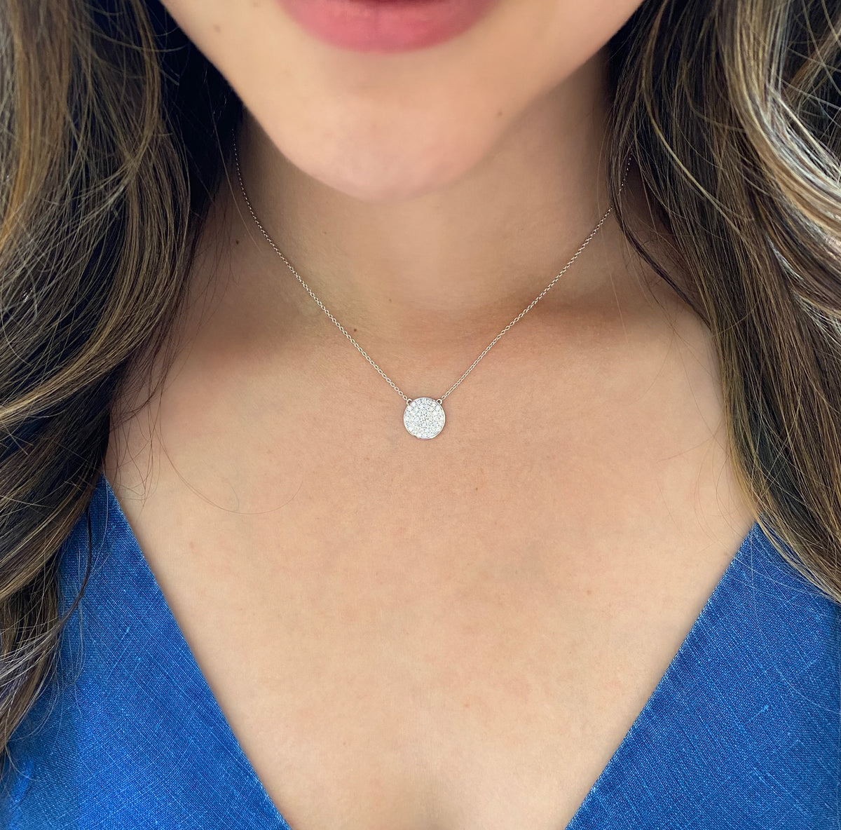 Female Model Wearing Pave Diamond Small Disc Pendant Necklace  -18K gold weighing 2.83 grams  -43 round diamonds totaling 0.50 carats.  Size width 12 millimeters.