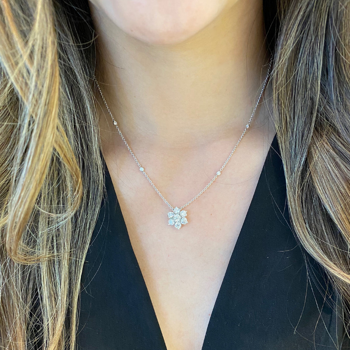 Female Model Wearing Diamond Flower Pendant with Bezel-Set Diamond Chain  -18K gold weighing 4.53 grams  -7 round bezel-set diamonds totaling 1.06 carats (pendant)  -4 round bezel-set diamonds totaling .08 carats (chain)  Size diameter 14 millimeters.