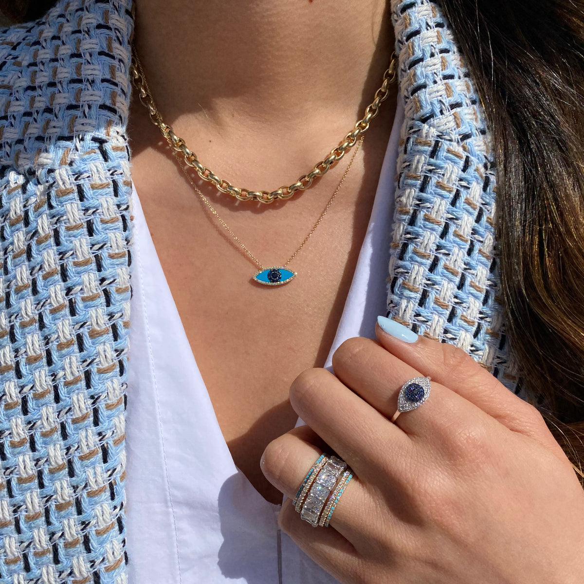 Female model wearing Diamond & Sapphire Evil Eye Ring- 14K yellow gold weighing 1.75 grams  - 0.02 ct black diamond  - 22 sapphires weighing 0.11 carats  - 58 round diamonds weighing 0.16 carats
