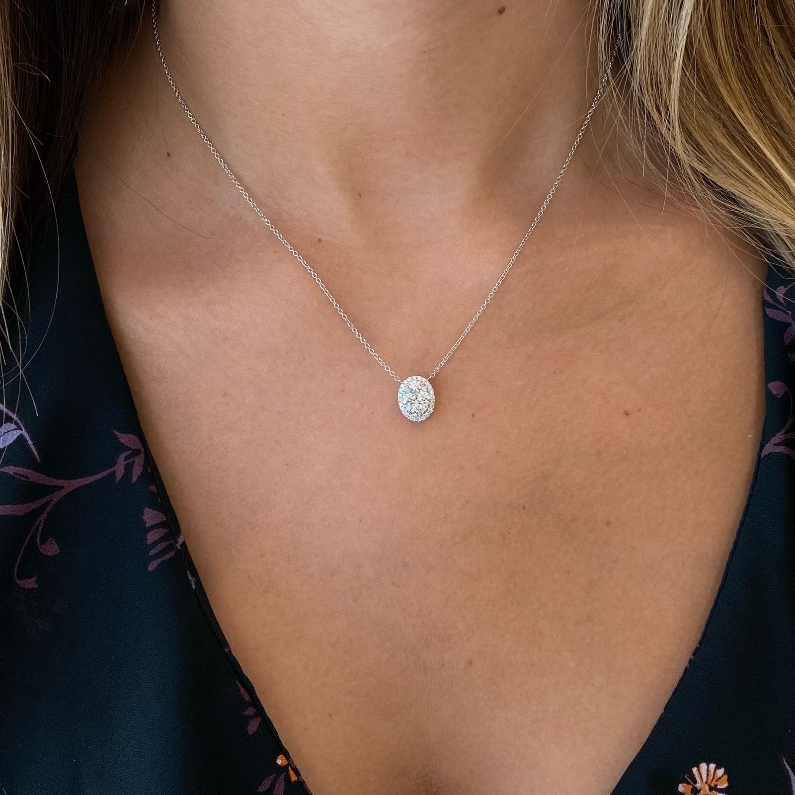 Diamond Halo Oval Pendant  - 18K white gold weighing 3.31 grams  - 34 round diamonds totaling 0.63 carats