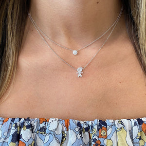 Female Model Wearing Diamond Stick Figure Girl Necklace  - 18K gold weighing 3.01 grams  - 32 round diamonds totaling 0.16 carats  - 4 princess-cut diamonds totaling 0.07 carats