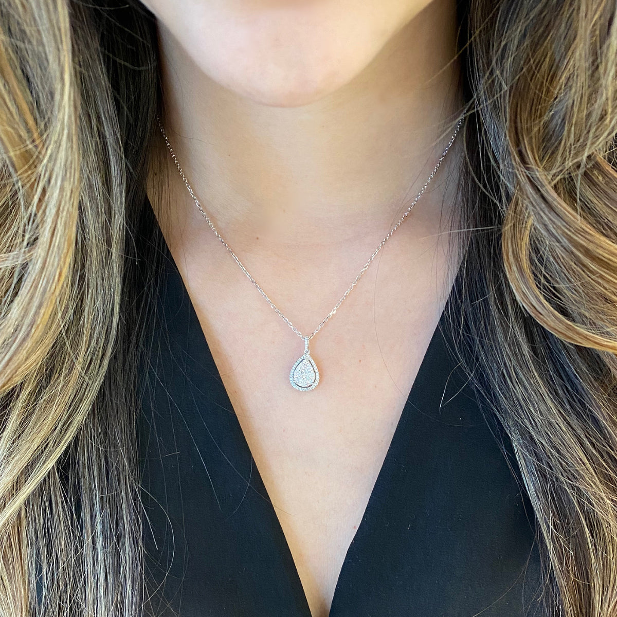 Female Model Wearing Diamond Cluster Teardrop Necklace  -18K weighing 1.63GR  -54 round diamonds totaling 0.38 carats  -3 round diamonds totaling 0.26 carats 