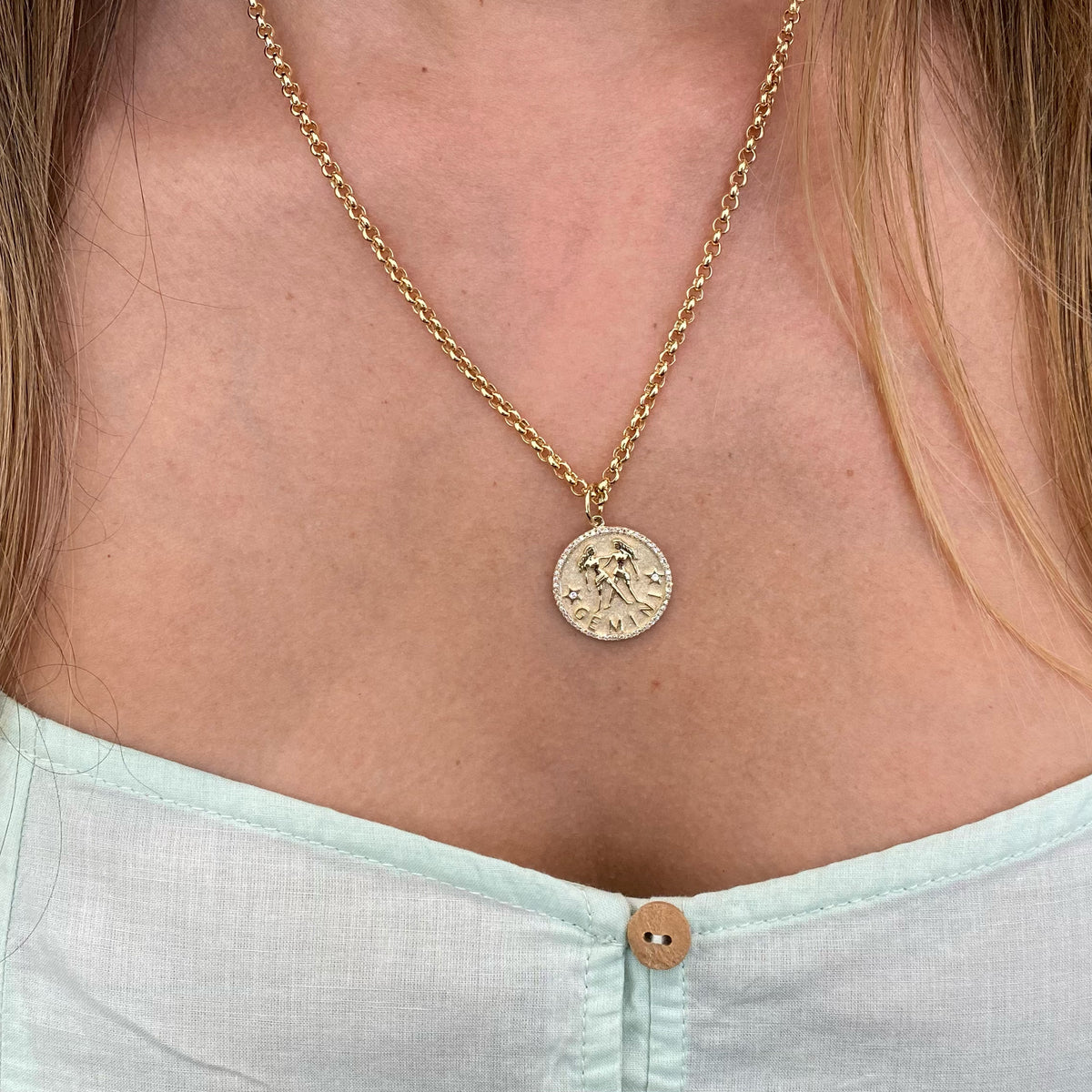 Female model wearing Diamond Zodiac Pendant - Gemini - 14K yellow gold weighing 4.25 grams - 58 round diamonds totaling 0.16 carats