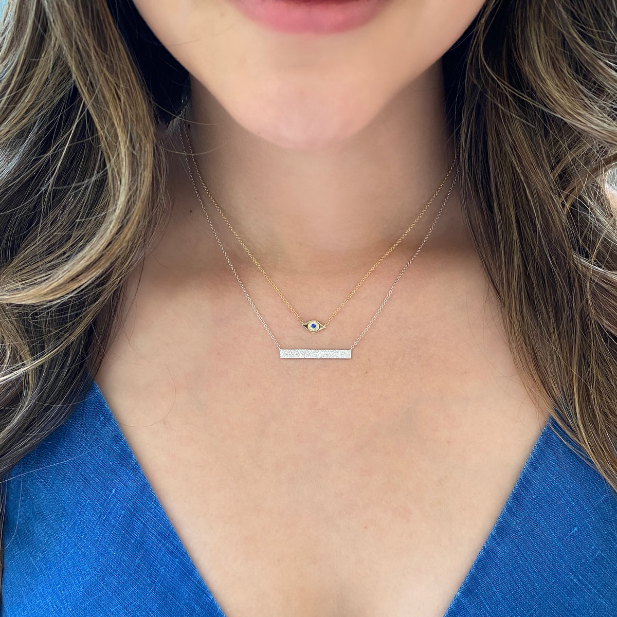 Female Model Wearing Sapphire & Diamond Evil Eye Pendant  - 14K yellow gold weighing 1.65 grams  - 10 round diamonds totaling 0.02 carats  - 0.03 ct sapphire