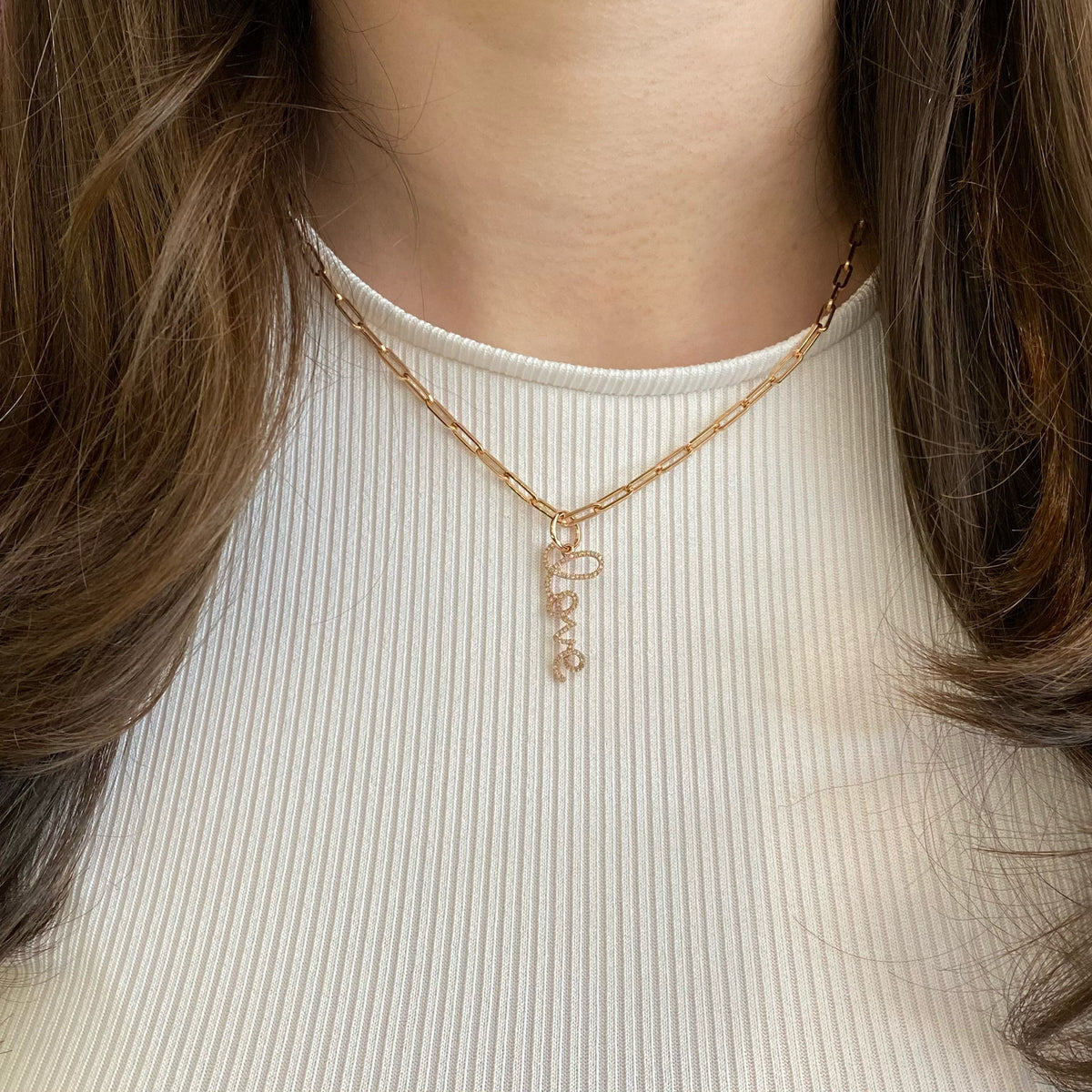 Female model wearing Large Diamond ‘Love’ Script Pendant  -14k rose gold weighing 1.52 grams  -90 round diamonds totaling 0.21 carats