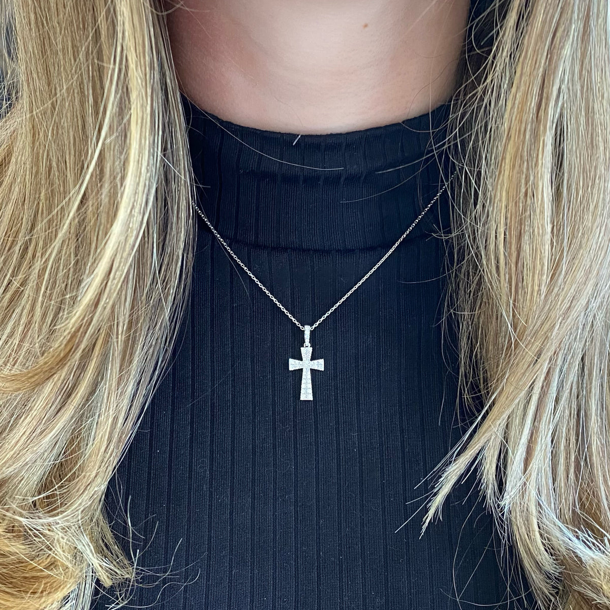 Female Model Wearing Diamond Flared Cross Pendant  - 18K gold weighing 1.67 grams  - 14K gold weighing 1.60 grams  - 38 round diamonds totaling 0.49 carats