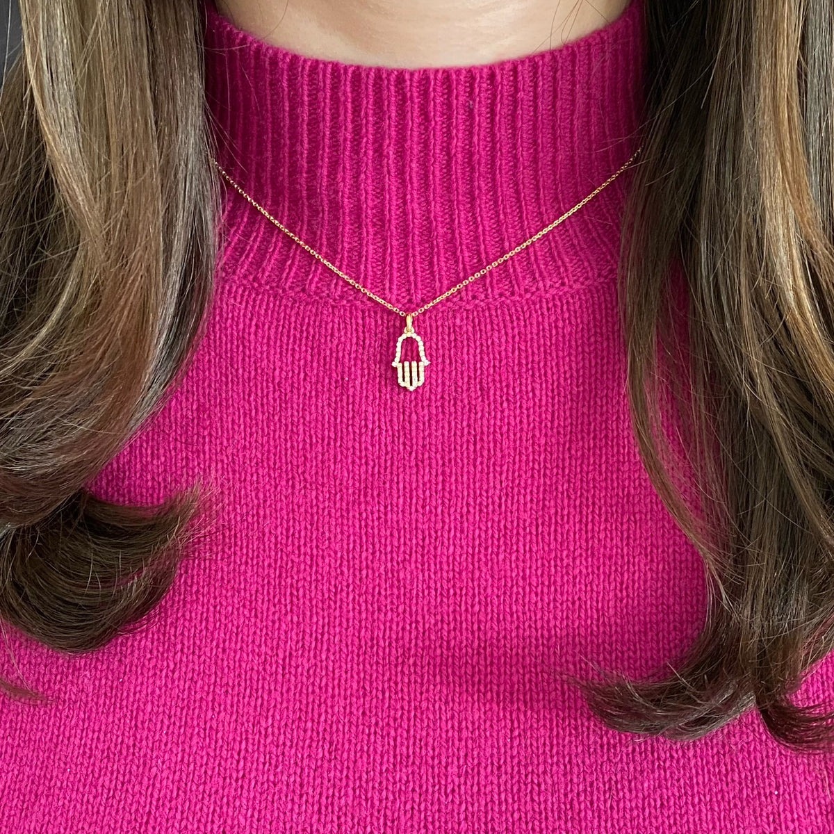 Female Model Wearing Diamond Hamsa Pendant Necklace     -14K gold weighing 3.5 grams  -39 round shared prong-set diamonds totaling 0.40 carats