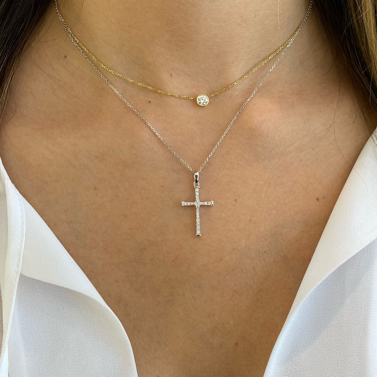 Female Model Wearing Diamond Skinny Cross Pendant Necklace  -14K gold weighing 2.85 grams  -20 round shared prong-set brilliant diamonds totaling 0.20 carats