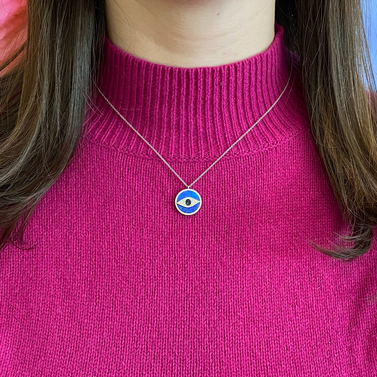 Female Model Wearing Opal & Diamond Evil Eye Pendant Necklace  -14K gold weighing 3.26 grams  -100 round diamonds totaling 0.23 carats  -7 sapphires weighing .07 carats  -1 opal weighing 3.21 grams