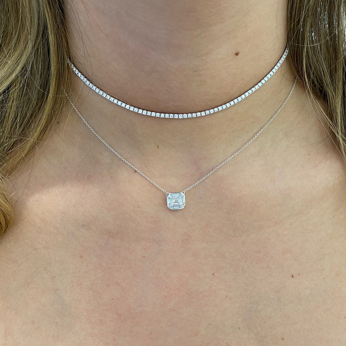Female Model Wearing Emerald-Cut Diamond Cluster Necklace  - 18K gold weighing 2.23 grams  - 0.22 ct emerald-cut diamond  - 8 baguette diamonds totaling 0.37 carats