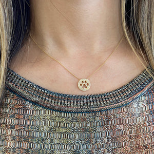 Female model wearing solid 14K yellow gold weighing 2.34 grams with 102 round diamonds totaling 0.23 carats Paw Print Cutout Pendant | Nuha Jewelers