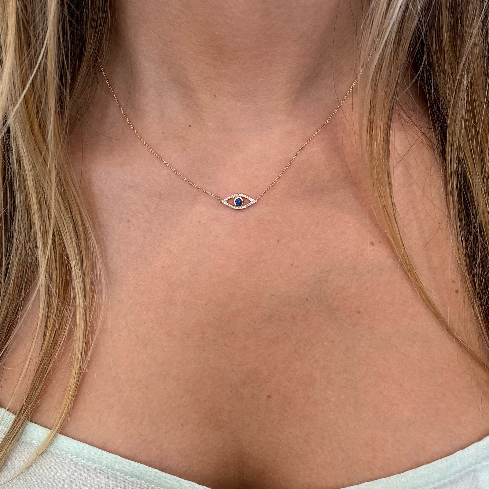 Sapphire & Diamond Open Evil Eye Pendant  - 14K yellow gold weighing 1.77 grams  - 26 round diamonds totaling 0.07 carats  - 0.11 ct sapphire