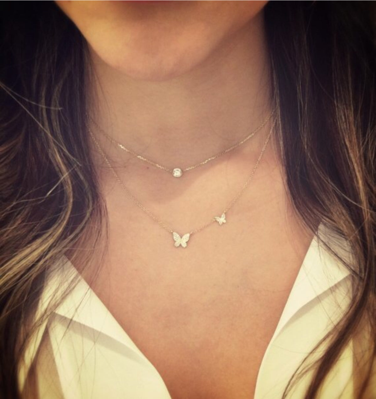 Female mode wearing Diamond Butterflies Necklace - 14K yellow gold weighing 1.90 grams -76 round pave-set diamonds totaling 0.18 carats. Size large butterfly width 9 millimeters, length 8 millimeters, small butterfly width 6 millimeters, length 5 millimeters.