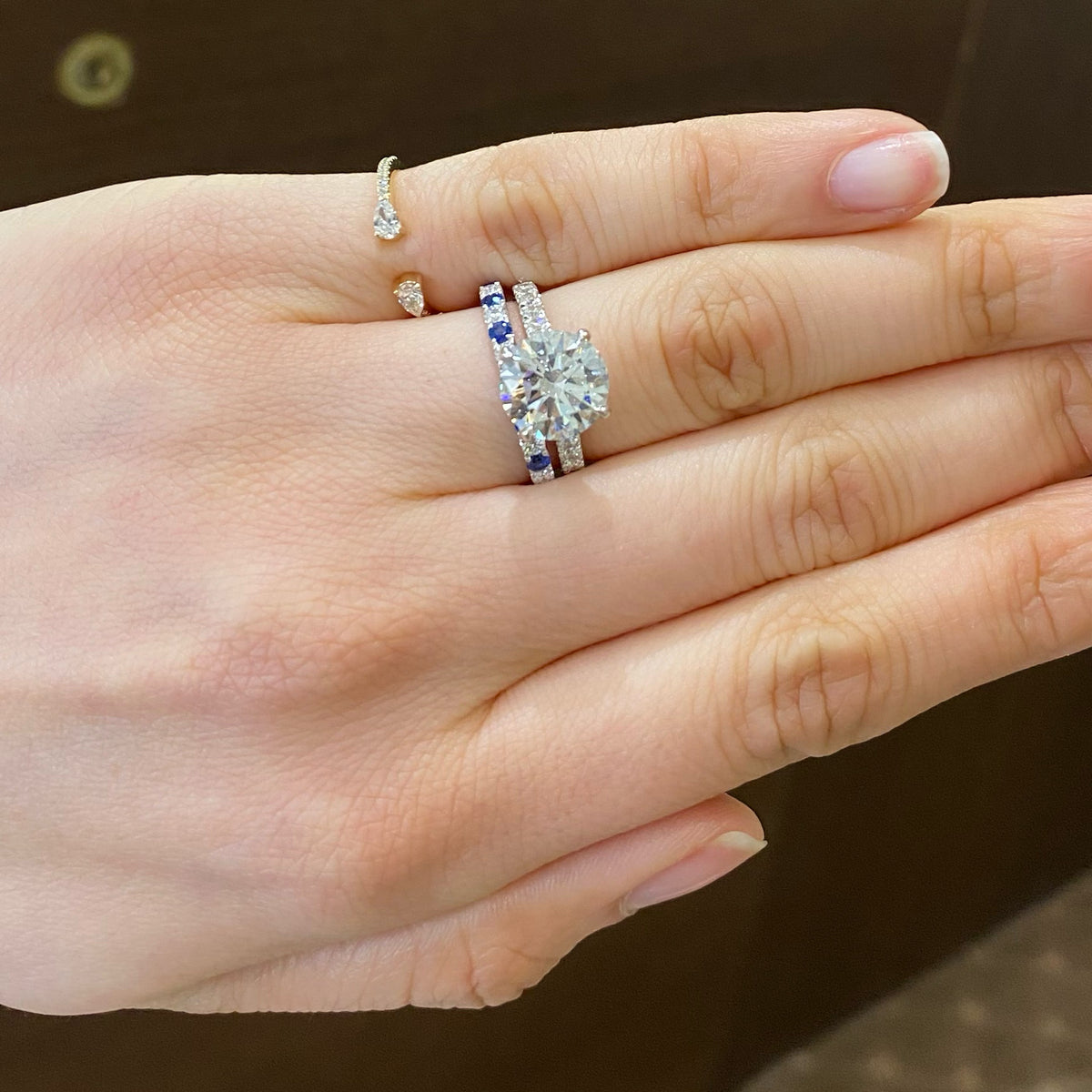 Female Model Wearing Sapphire & Diamond Band  - 18K gold weighing 2.0 grams  - 7 round diamonds totaling 0.22 carats  - 8 sapphires totaling 0.35 carats