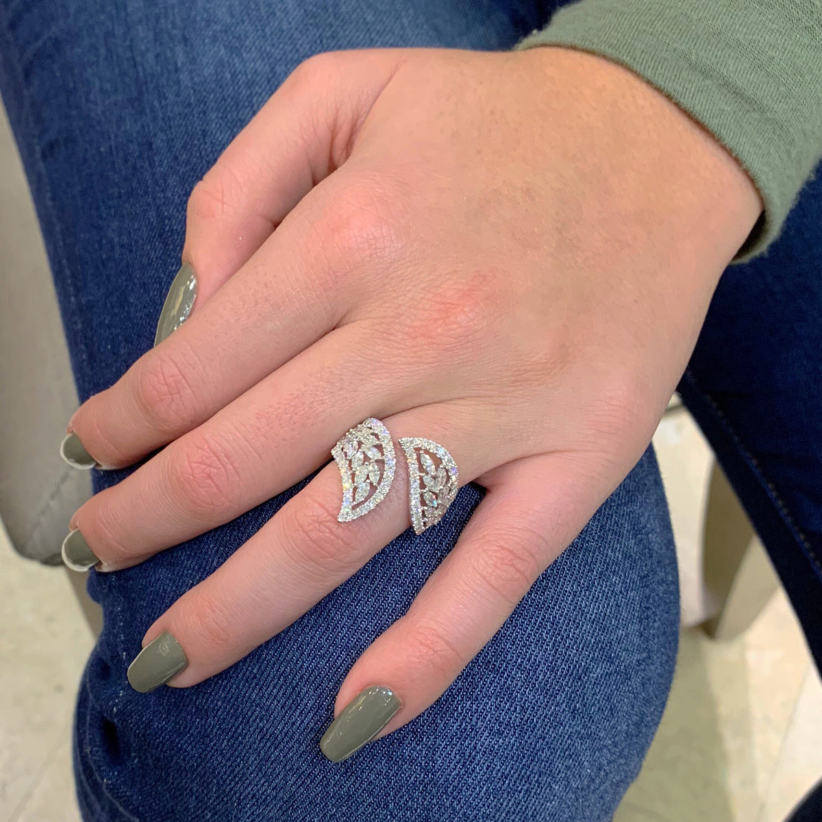 Female Model Wearing Leaf-Shaped Diamond Ring  -18k gold 8.83 grams  -22 shared prong-set marquise diamonds 1.12 carats  -61 round 4 prong-set diamonds .72 carats.  -22.5 millimeters wide