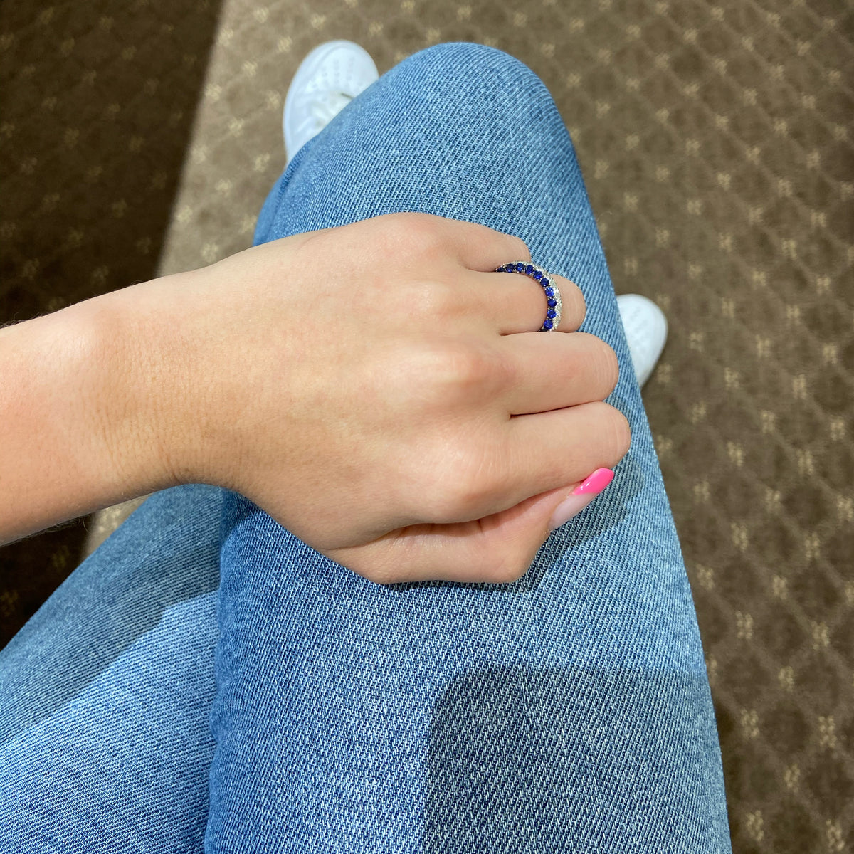 Female model wearing Sapphire gemstone & diamond eternity wedding band -18k gold weighing 3.91 grams  -23 round diamonds weighing 1.89 carats  -46 sapphire gemstones weighing 2.79 carats