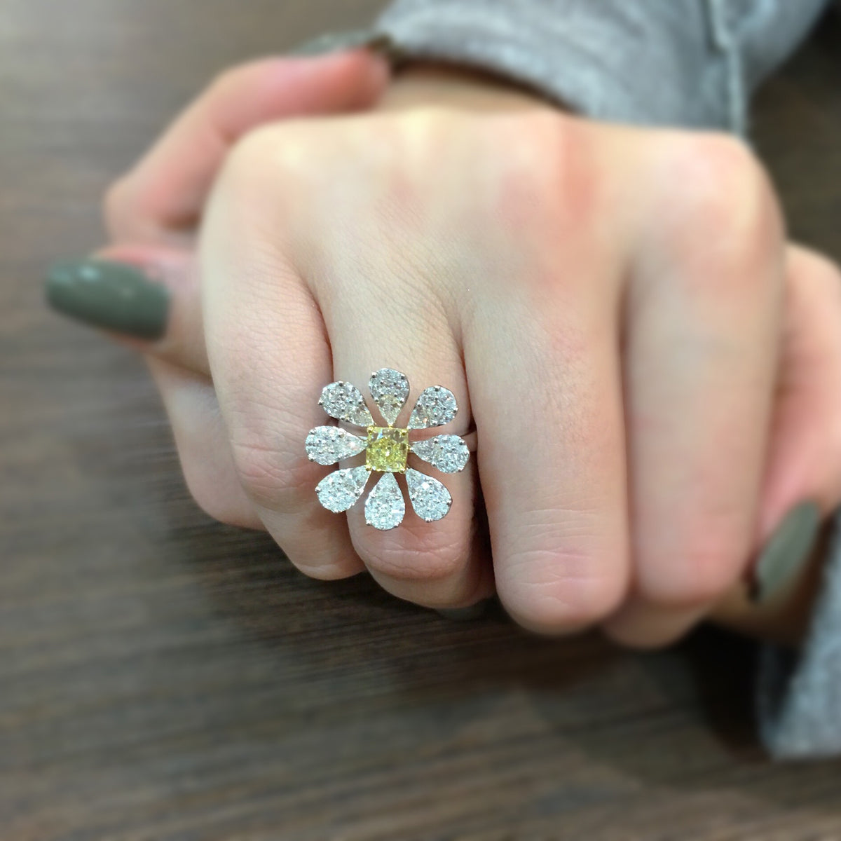 Female Model Wearing Blossoming Diamond Flower Ring  Center radiant cut diamond weighs .76cts. GIA report # 61737737614.  Size width 20.3 millimeters.