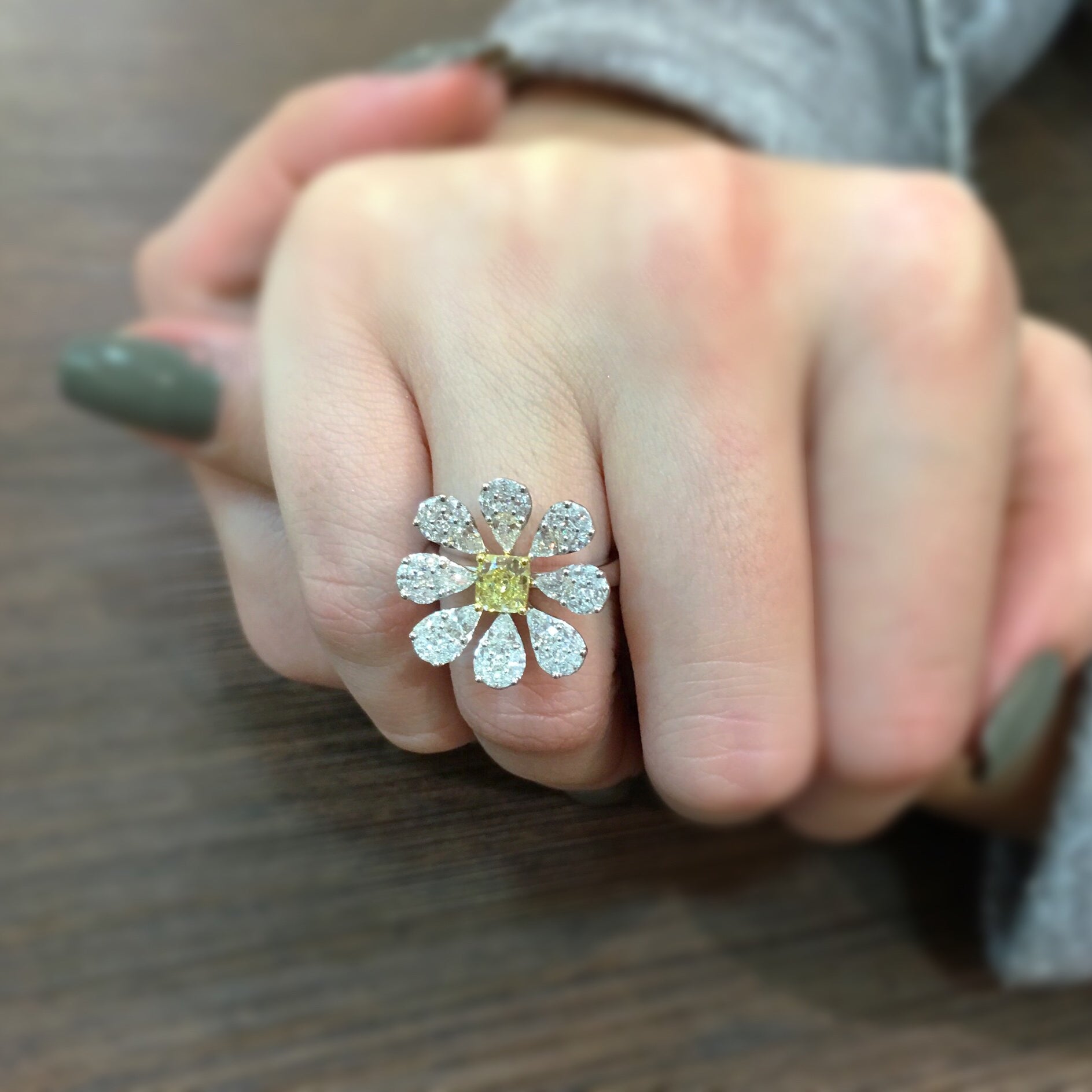 Female Model Wearing Blossoming Diamond Flower Ring  Center radiant cut diamond weighs .76cts. GIA report # 61737737614.  Size width 20.3 millimeters.