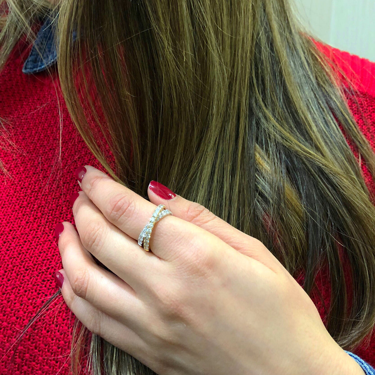 Female Model Wearing Two-tone Interlock Diamond Ring  18k gold, 4.06 grams, 26 round shared prong-set brilliant diamonds 1.21 carats.  Size width 6.3 millimeters.