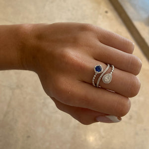 Female model wearing Sapphire cushion & diamond teardrop bypass ring - 18K gold weighing 4.94 grams - 75 round diamonds totaling 0.41 carats - 0.49 ct cushion brilliant-cut sapphire